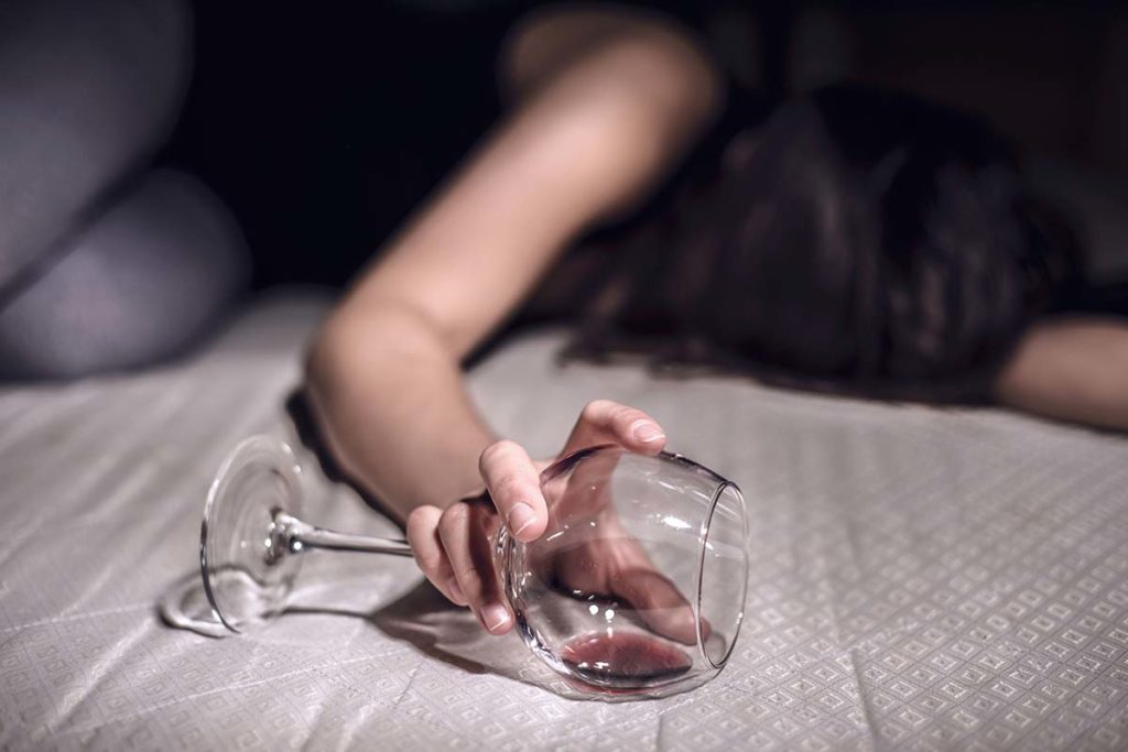woman passed out with wine glass in hand suffering and wondering how dangerous is an alcohol blackout