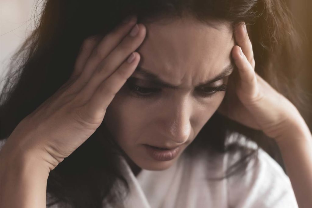 signs of anxiety, woman with her hands at her temples in distress