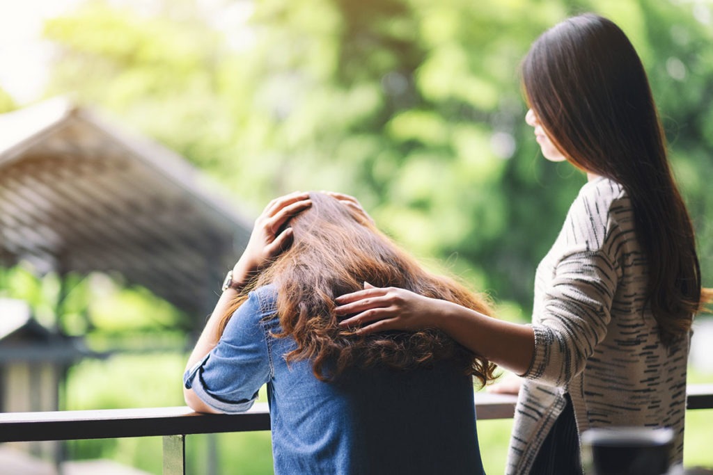 woman comforting another woman having learned the signs of codependency
