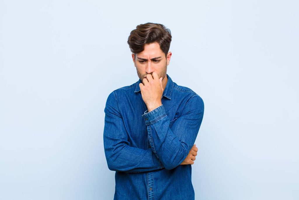 Stages of Alcoholism, man in blue shirt against blue background thinking