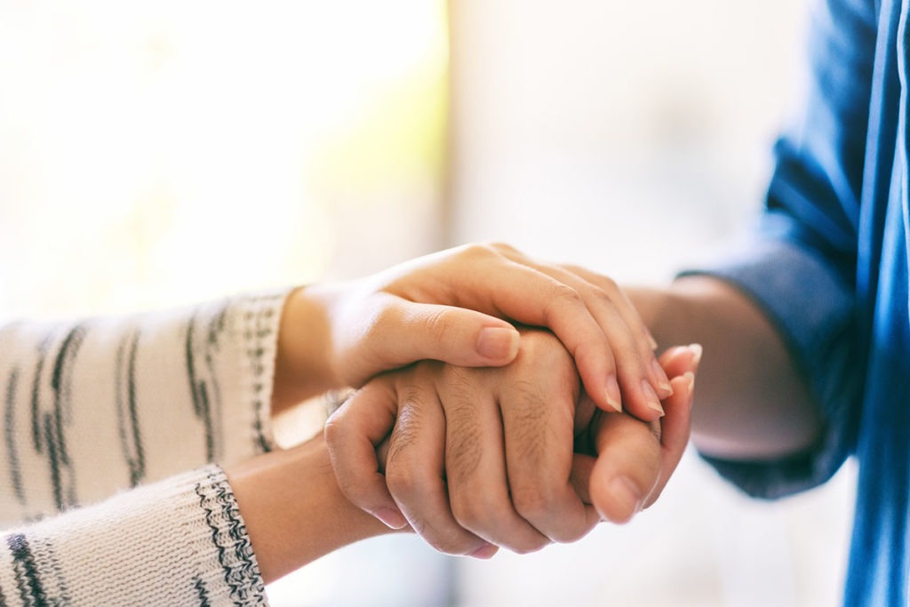 two people holding hands show how to help an addict