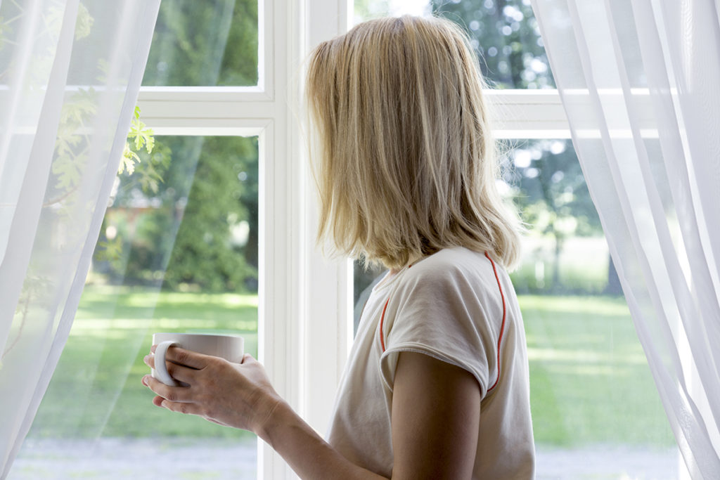 woman looking out window experiencing anxiety during a pandemic