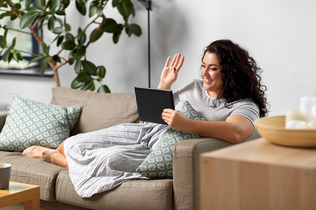 woman with tablet on couch learning about coping with isolation during coronavirus