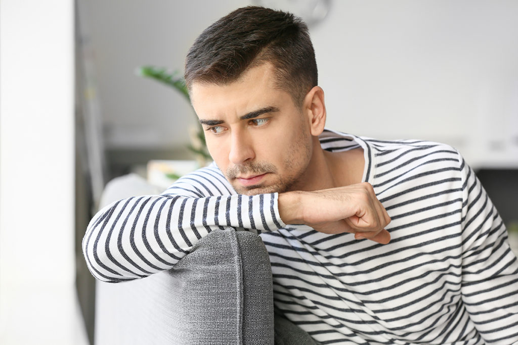 man thinking on couch about dangers of mixing substances