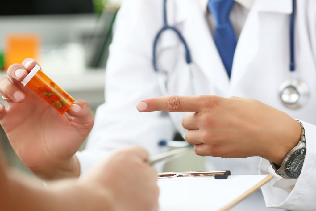 doctor pointing to a bottle of pills and explaining what makes prescription opioids so dangerous