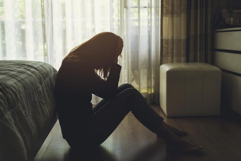 Person sitting on floor and realizing they have a psychological dependence on a substance