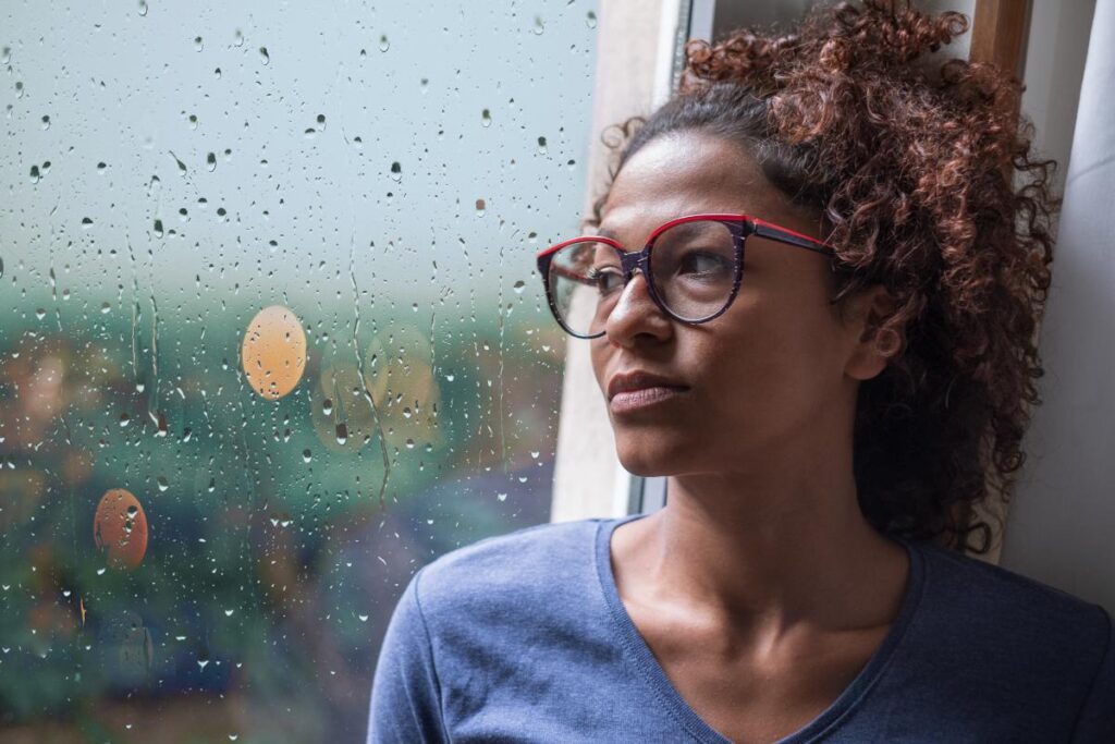 Person looking out window and wondering, "How are mental illness and addiction linked?"
