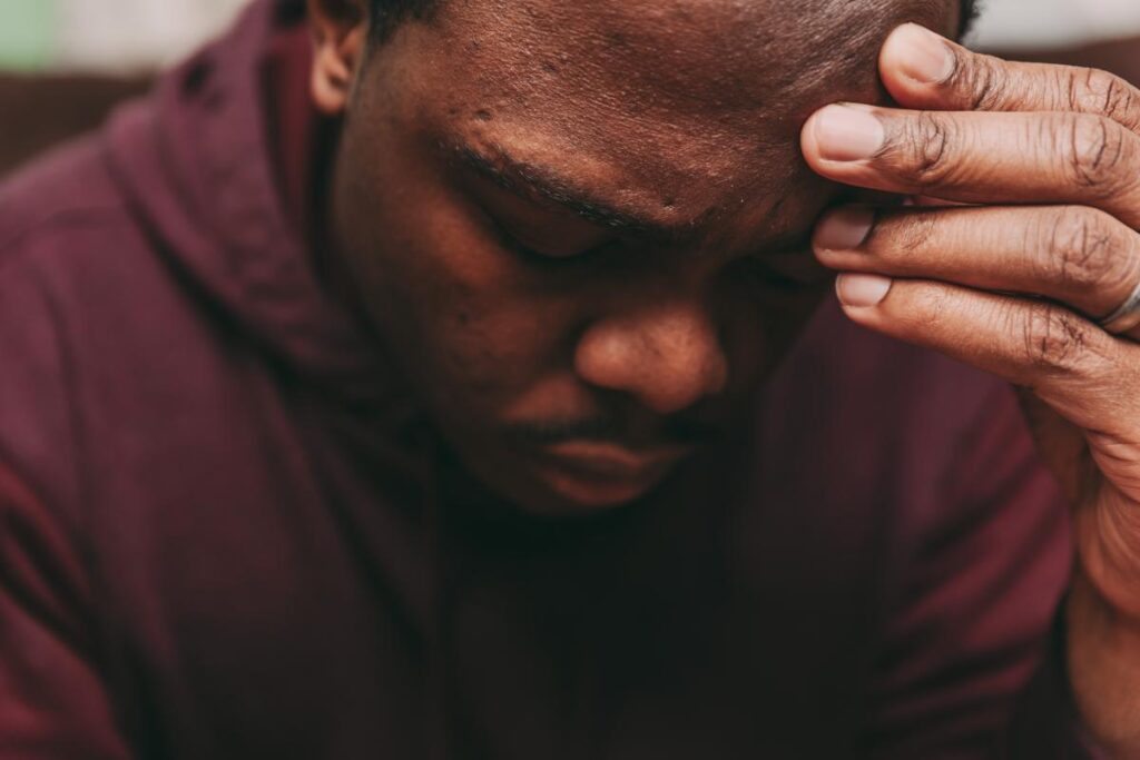 Man with hand on his forehead, as he is recognizing signs of kratom addiction in himself