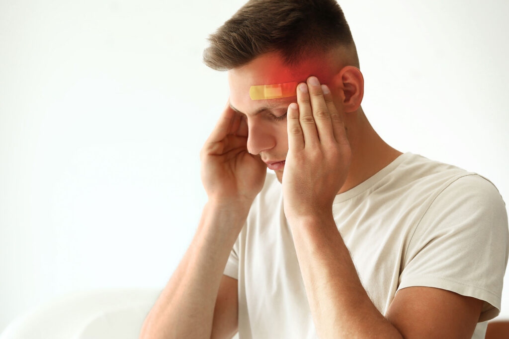 Man touching his temples and thinking, "Can you drink if you have a concussion?"