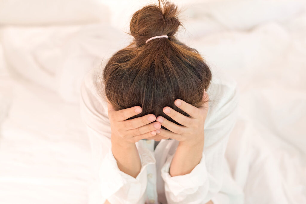 A woman with her face in her hands, thinking, "Can you drink with post-concussion syndrome?"