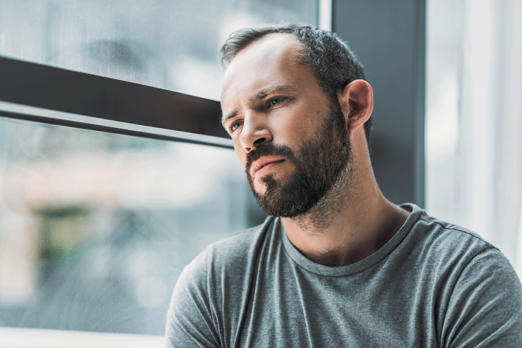 Man by window, wondering, "What are the dangers of non-alcoholic beer?"