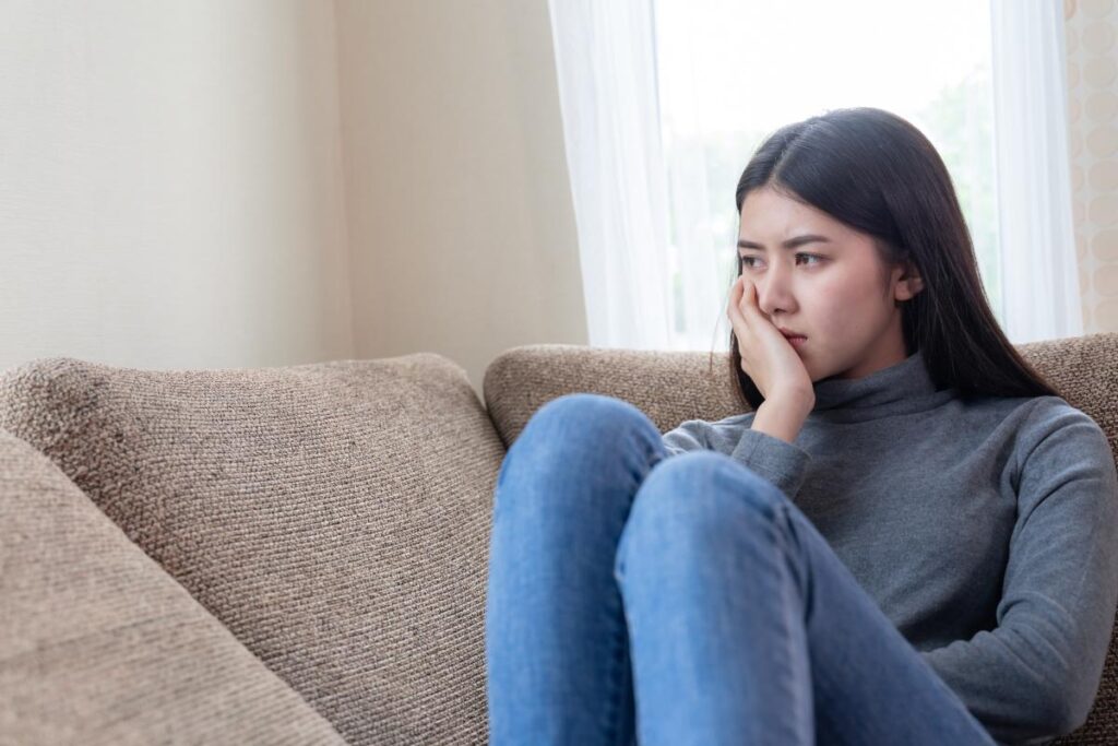 Person sitting on couch and wondering what the signs of depressant addiction are
