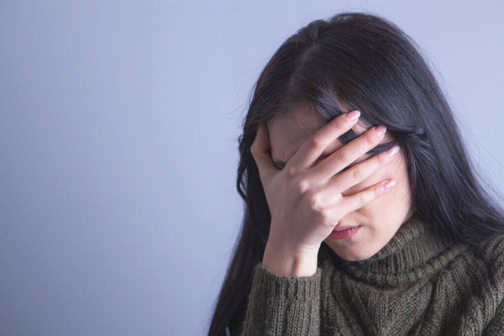 Person covering their face and wondering how alcohol affects the brain